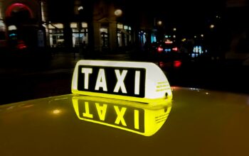 Close-up of a glowing taxi sign reflecting in the night city street, capturing urban nightlife.